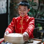 A Young Boy Holding a Chinese steamer pot