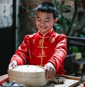 A Young Boy Holding a Chinese steamer pot